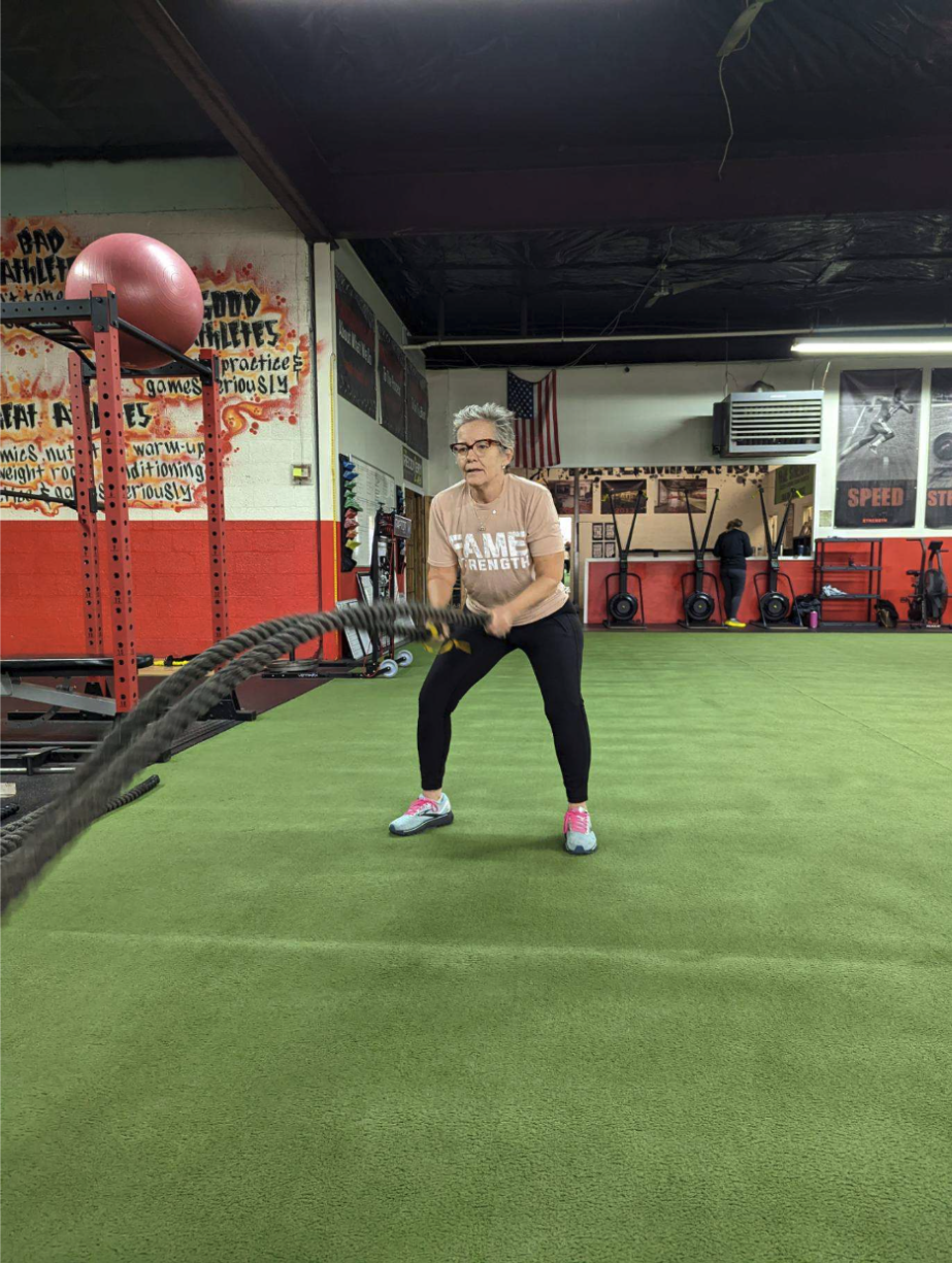 Fame Strength adult member working battle ropes during her training session
