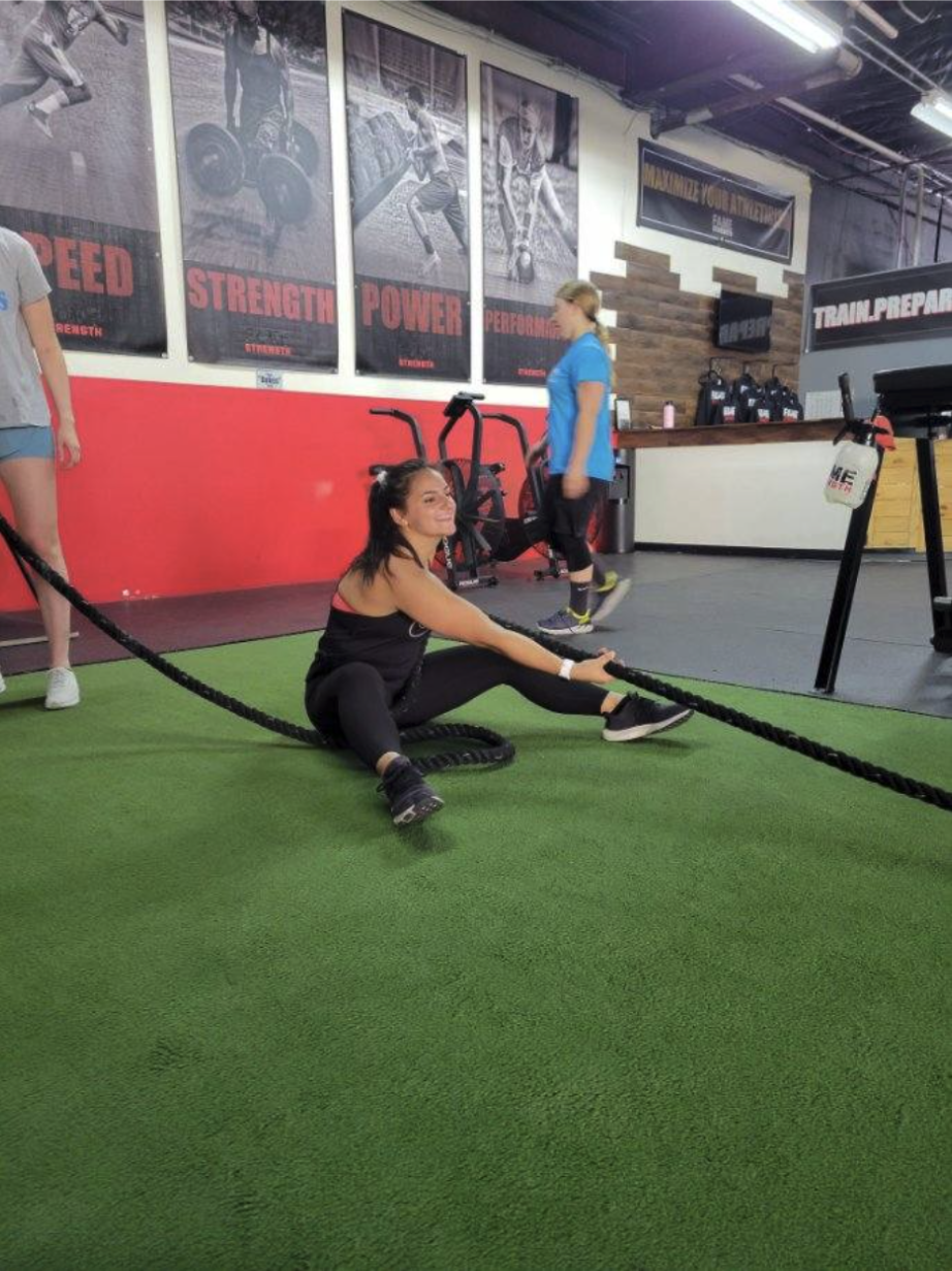 Fame Strength adult member training with battle ropes on the turf
