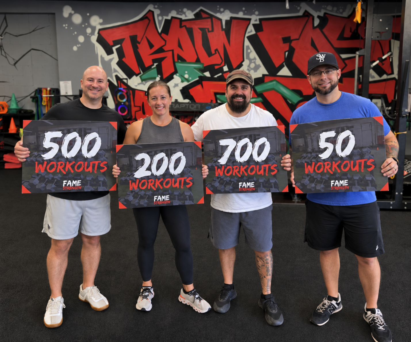 Four Fame Strength members celebrating 500, 200, 700, and 500 workout milestones